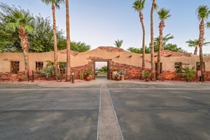 A building entrance with a brick archway, palm trees, and potted plants.