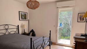 Et soveværelse med en seng, et natbord, en lampe og et billede på væggen.