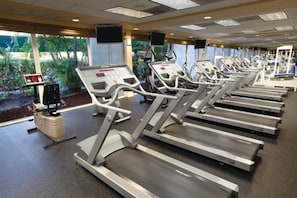 A gym with treadmills, stationary bikes, and a rowing machine. - Pompano Beach | Couples Golf Getaway | Pool + Golf (Pompano Beach)