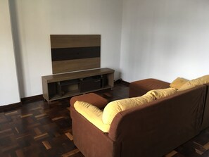 A living room with a brown sofa, a flat-screen TV, and a wooden entertainment unit. - Ap na rua das flores em Curitiba (Curitiba)