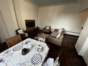 A compact living space with a sofa, a TV, a dining table with chairs, and a small coffee table. - Ap na rua das flores em Curitiba (Curitiba)
