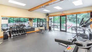 Ein Fitnessraum mit Trainingsgeräten, einem Spiegel und großen Fenstern.