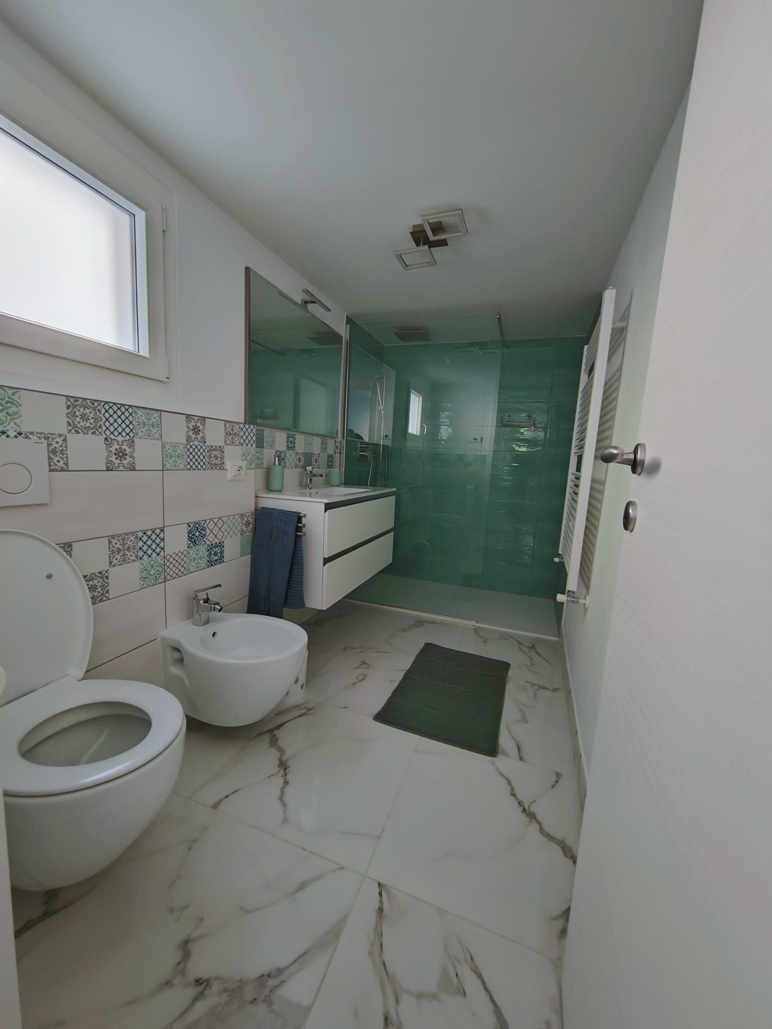 Ein Badezimmer mit Toilette, Bidet, Waschbecken und Duschbereich.