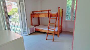 Una habitación con literas, una escalera, una mesita y una ventana.