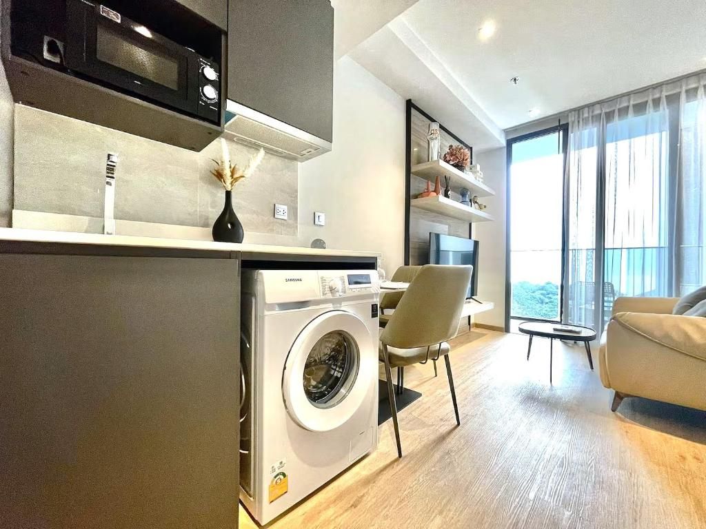 A modern kitchen with a built-in washer and dryer, a dining area with a table and chairs, and a large window offering a view.