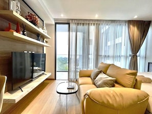 A modern living room with a sofa, a coffee table, and a flat-screen TV. - Andromeda Condominium Pattaya (Muang Pattaya)
