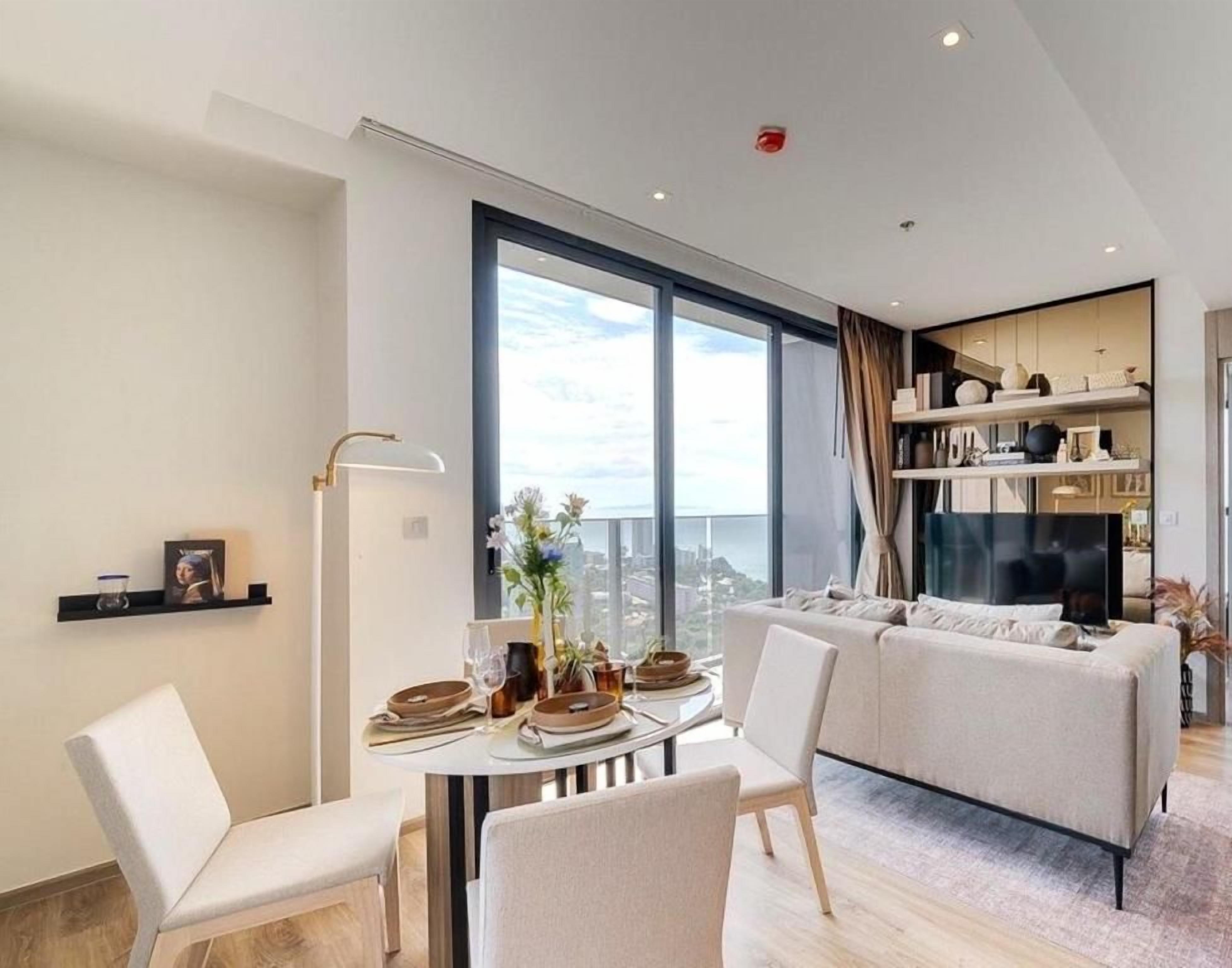 Ein modernes Wohnzimmer mit Essbereich, großen Fenstern und Blick auf die Stadt.