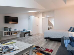 Ein modernes Schlafzimmer mit Bett, Schreibtisch, Fernseher und Kleiderschrank.