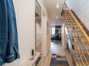 Ein Flur mit einer Holztreppe, einer Sitzecke und einem Kleiderschrank.