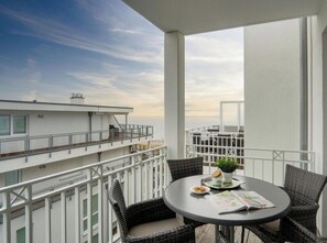 A balcony with a round table, wicker chairs, and a potted plant. - Sea View Villa, Apartment 44 "seaside" (Grossenbrode)
