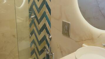 A modern bathroom with a glass shower enclosure, a white toilet, and a vanity with two sinks.