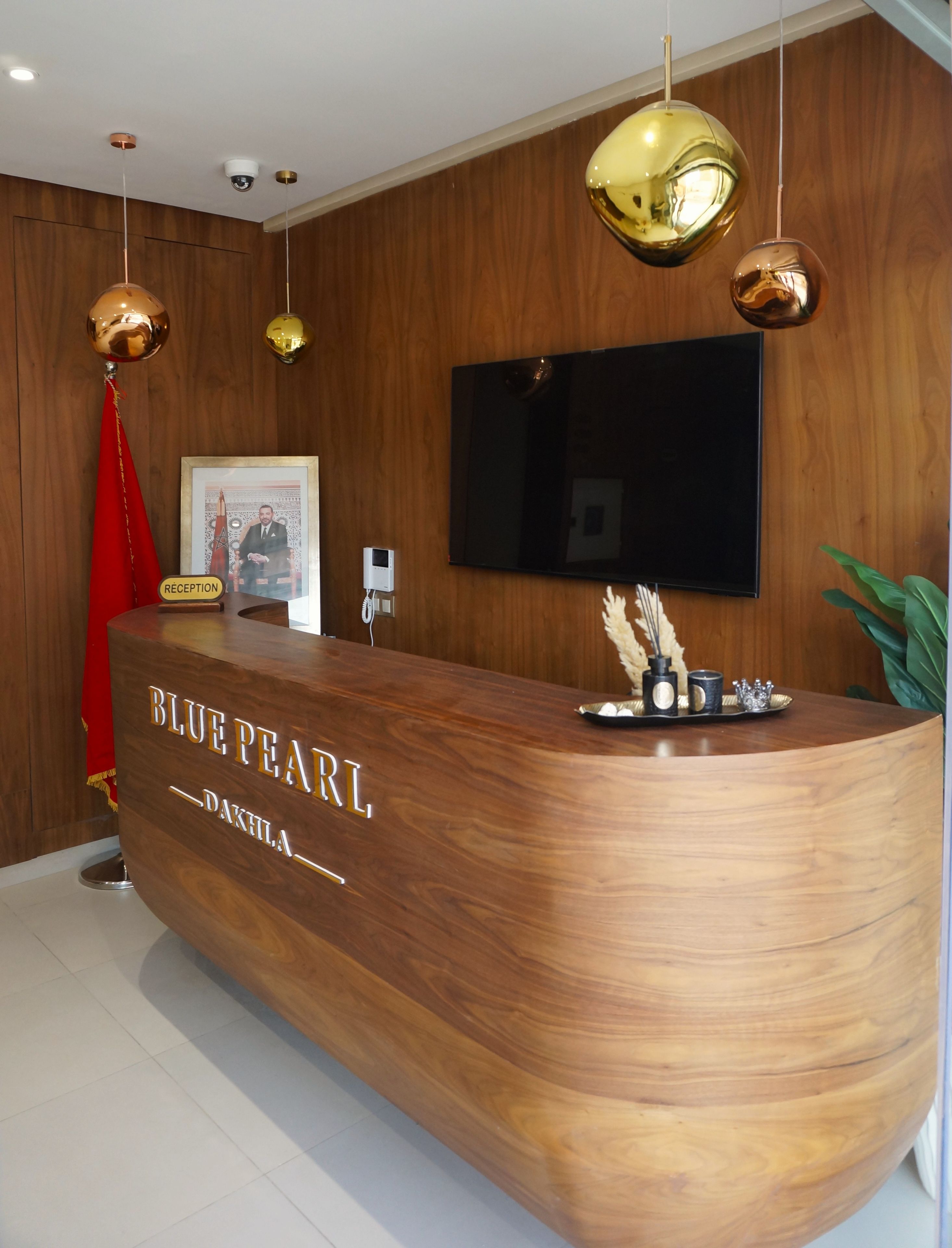 A reception desk with a wooden finish, a flat-screen TV mounted on the wall, and a reception sign.