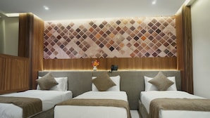 Quarto de hotel com design moderno, apresentando uma cama grande com duas almofadas e cabeceira com padrão decorativo.