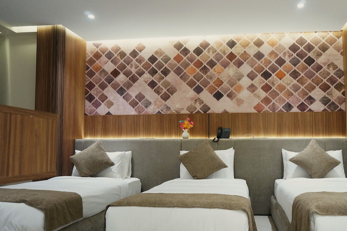 Ein Hotelzimmer im modernen Stil, mit einem großen Bett, zwei Kissen und einem Kopfende mit einem gemusterten Design.