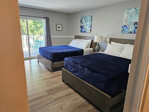 Een hotelkamer met twee bedden, een schuifglasdeur naar een balkon en kunstwerken aan de muur.