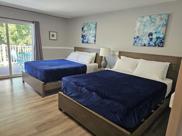 Een hotelkamer met twee bedden, een schuifglasdeur naar een balkon en kunstwerken aan de muren.