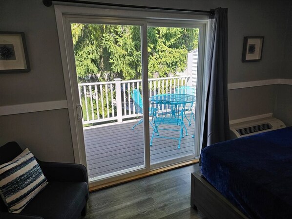 A room with a large sliding glass door leading to an outdoor deck with a blue metal table and chairs.