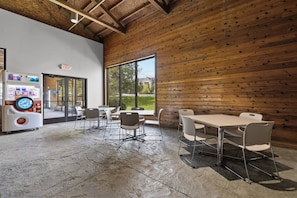 Un espace intérieur moderne avec un mur en bois, un distributeur automatique et une table avec des chaises.