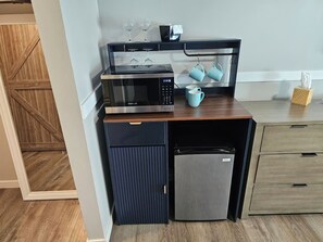 A compact kitchen with a microwave, a small refrigerator, and a coffee maker.