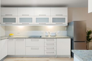 A modern kitchen with white cabinets, a stainless steel refrigerator, and a countertop with a toaster and kettle. - Sea Spray A109 (Cape Town)
