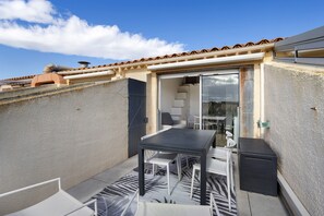 A rooftop terrace with a table and chairs, a sliding glass door, and a view of the sky. - Apartment 'Studio Plage et Village' with Sea View, Shared Pool and Air Conditioning (Le Barcarès)