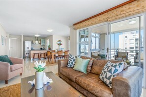 Eine moderne Wohnung mit Wohnzimmer, Essbereich und Küche. Ein großes Fenster bietet Blick auf die Stadt.