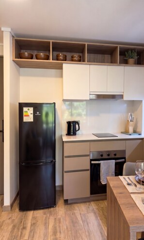 A modern kitchen with a black refrigerator, stainless steel oven, and wooden cabinets. - Vista Bulnes Santiago by Domus Travels (Santiago)
