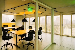 A conference room with a large table, multiple chairs, and pendant lighting. - Vista Bulnes Santiago by Domus Travels (Santiago)