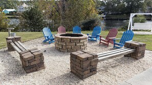 Un foyer entouré de fauteuils Adirondack, une balançoire et un sol recouvert de gravier.