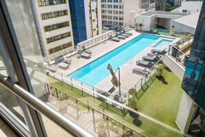Ein Pool auf dem Dach mit Liegestühlen und einer Glasbrüstung.