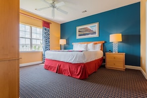 A hotel room with a bed, two bedside tables, a ceiling fan, a window with curtains, and a painting on the wall. - Myrtle Beach | Poolside Leisure Break | Lazy River + Pool | 2BR (Myrtle Beach)