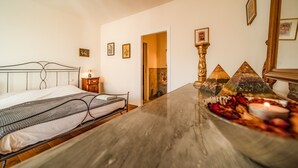 A bedroom with a bed, bedside table, and a decorative centerpiece with fruits and candles. - defaultName (Monte Castello di Vibio)