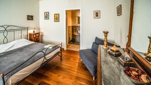 A bedroom with a bed, a desk, a chair, a mirror, and a small table with decorative items. - defaultName (Monte Castello di Vibio)
