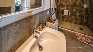 A bathroom with a large sink, a mirror, a shower area, and a patterned wall. - defaultName (Monte Castello di Vibio)