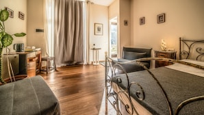 A hotel room with a bed, a desk, a chair, a potted plant, and a view of the outdoors. - defaultName (Monte Castello di Vibio)