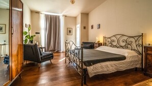 A bedroom with a metal bed frame, a wooden wardrobe, a chair, and a bedside table with a lamp. - defaultName (Monte Castello di Vibio)