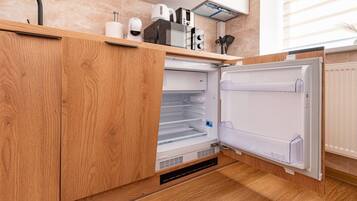 A kitchen with wooden cabinets, a built-in microwave, and a refrigerator.