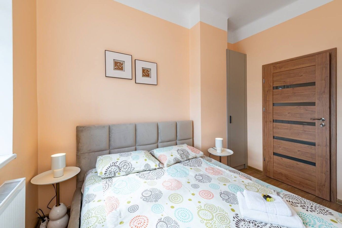 Ein Schlafzimmer mit einem Bett, zwei Nachttischen, einem Schrank und zwei an der Wand hängenden Bildern.