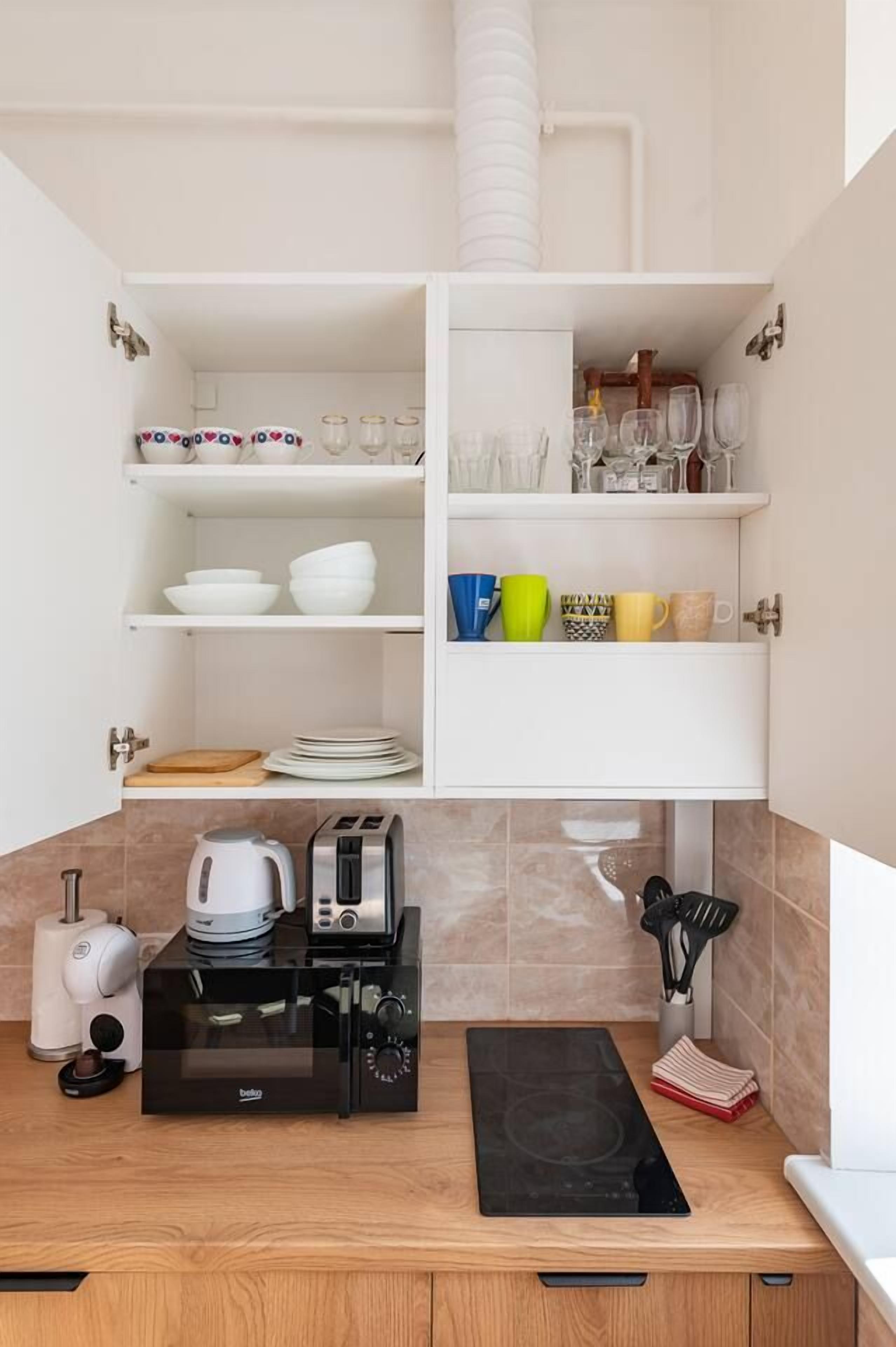 Una cocina compacta con armarios blancos, estufa integrada y cafetera.