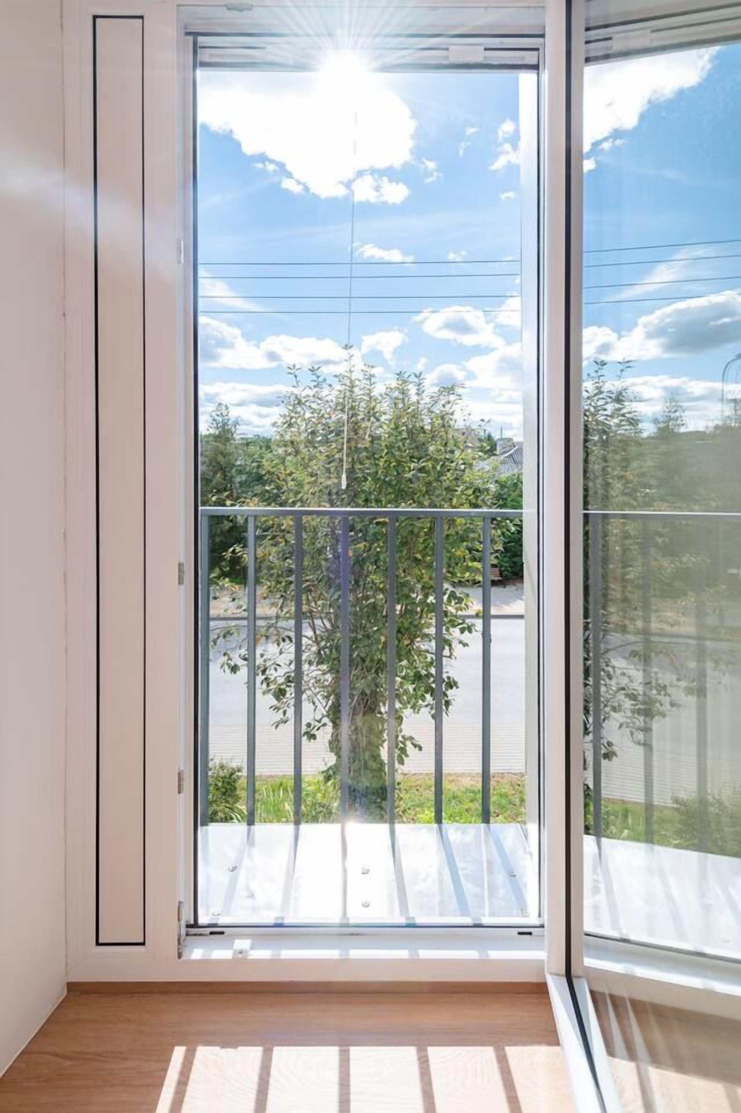 A room with a large sliding glass door leading to a balcony with a metal railing.