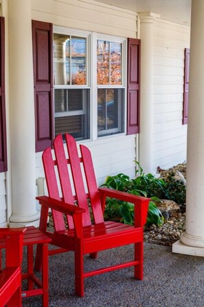 A red Adirondack chair outside a house with white siding and dark shutters. - Lincoln NH | Ski Retreat | Pool, Near Loon & Hiking Trails (Lincoln)