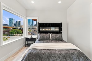 A bedroom with a city view, a fireplace, and a modern bed. - Modern 3BR Home Near Midtown & Atlantic Station (Atlanta)