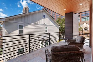 A balcony with a view of a building, a wicker chair, and a metal railing. - Modern 3BR Home Near Midtown & Atlantic Station (Atlanta)