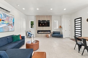 A modern living room with a fireplace, a flat-screen TV, and a dining area with chairs. - Modern 3BR Home Near Midtown & Atlantic Station (Atlanta)