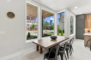 A modern kitchen with a large window, a dining table with chairs, and a view of the neighborhood. - Modern 3BR Home Near Midtown & Atlantic Station (Atlanta)