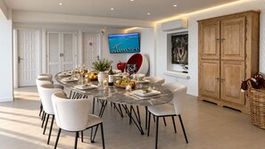 A dining area with a round table, chairs, and a television mounted on the wall. - Luxury Villa with a Heated Pool and Panoramic Ocean Views (Santiago del Teide)