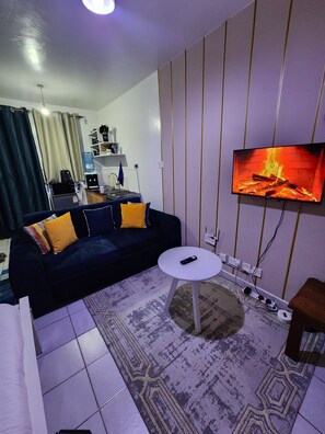 Ein Wohnzimmer mit einer Couch, einem Couchtisch, einem an der Wand montierten Fernseher und einem gemusterten Teppich.