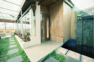 Un edificio moderno con entrada de vidrio, pared de ladrillo y un pequeño jardín con piedras para caminar.