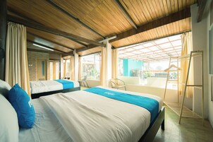 A hotel room with two beds, a balcony, and a view of the outside.
