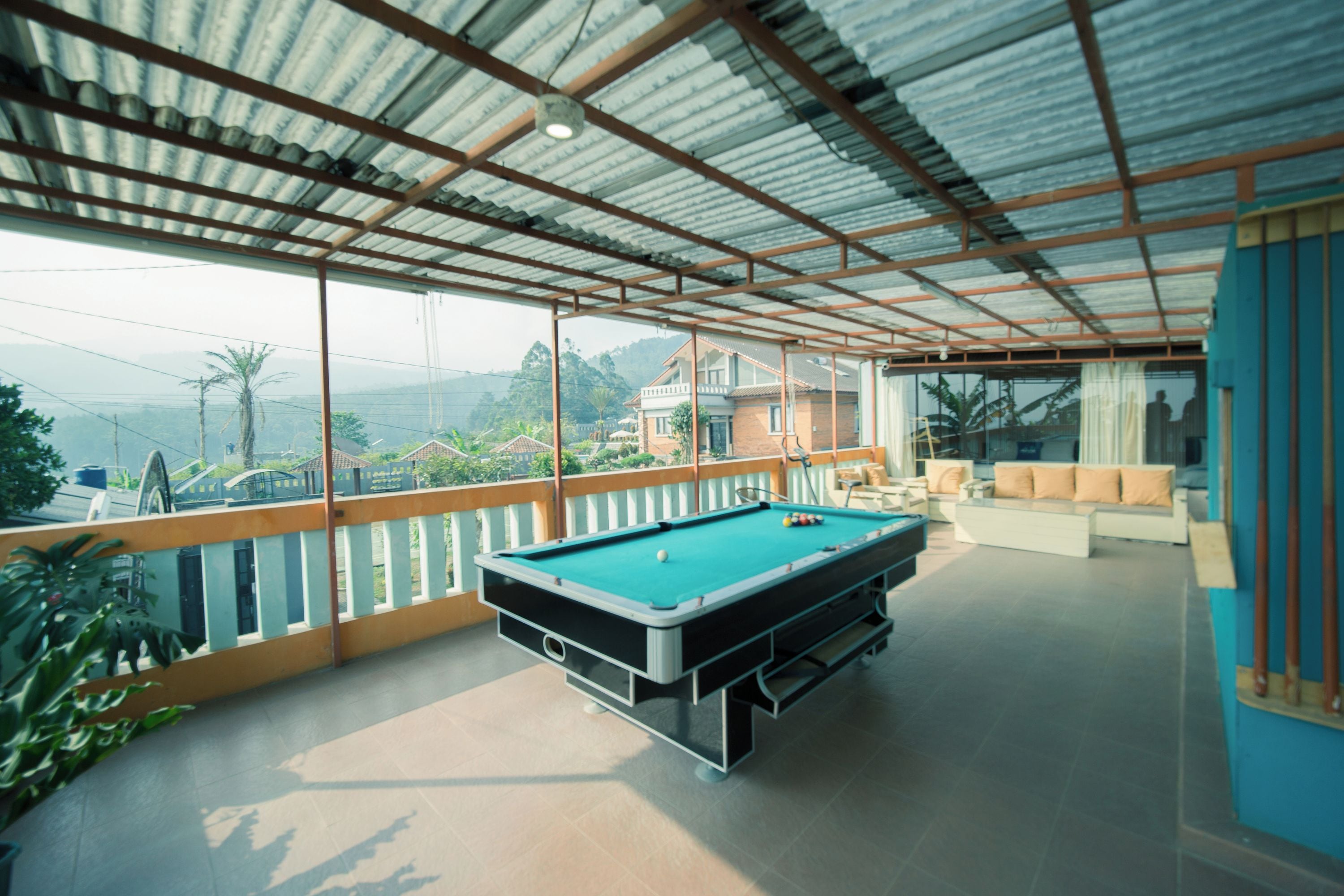 A pool table in a room with a view of a residential area and hills.